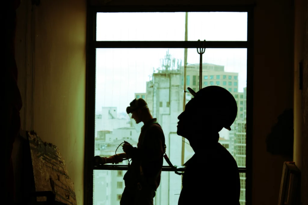 Two workers look upwards for information while working on a hydraulic pump