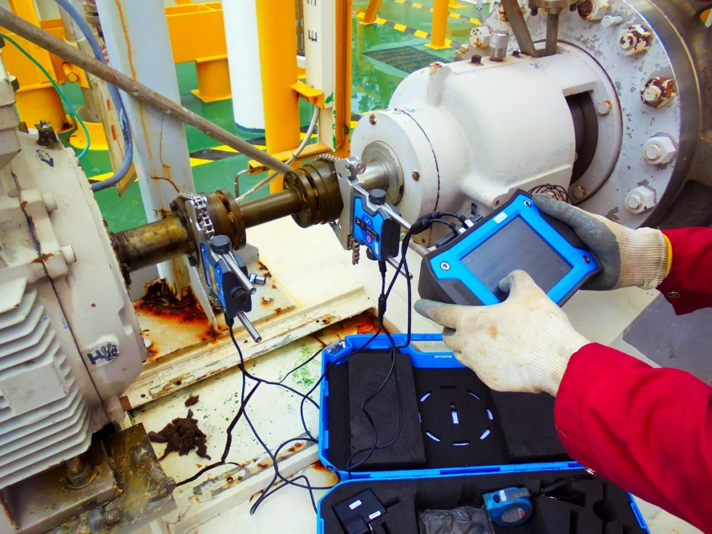 Technician using a laser shaft alignment tool to calibrate pump and motor alignment during industrial pump maintenance