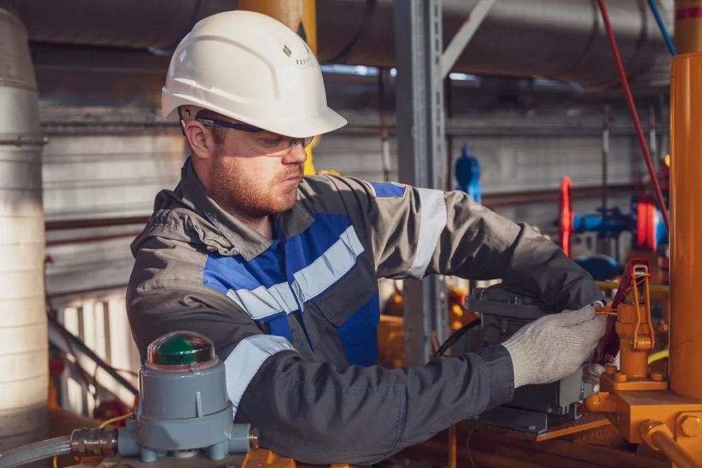 Engineer performing routine pump system inspection inside an industrial facility, adjusting valve settings and control panels