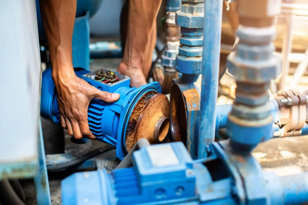 Technician removing a corroded pump impeller for replacement during mechanical pump repair and maintenance