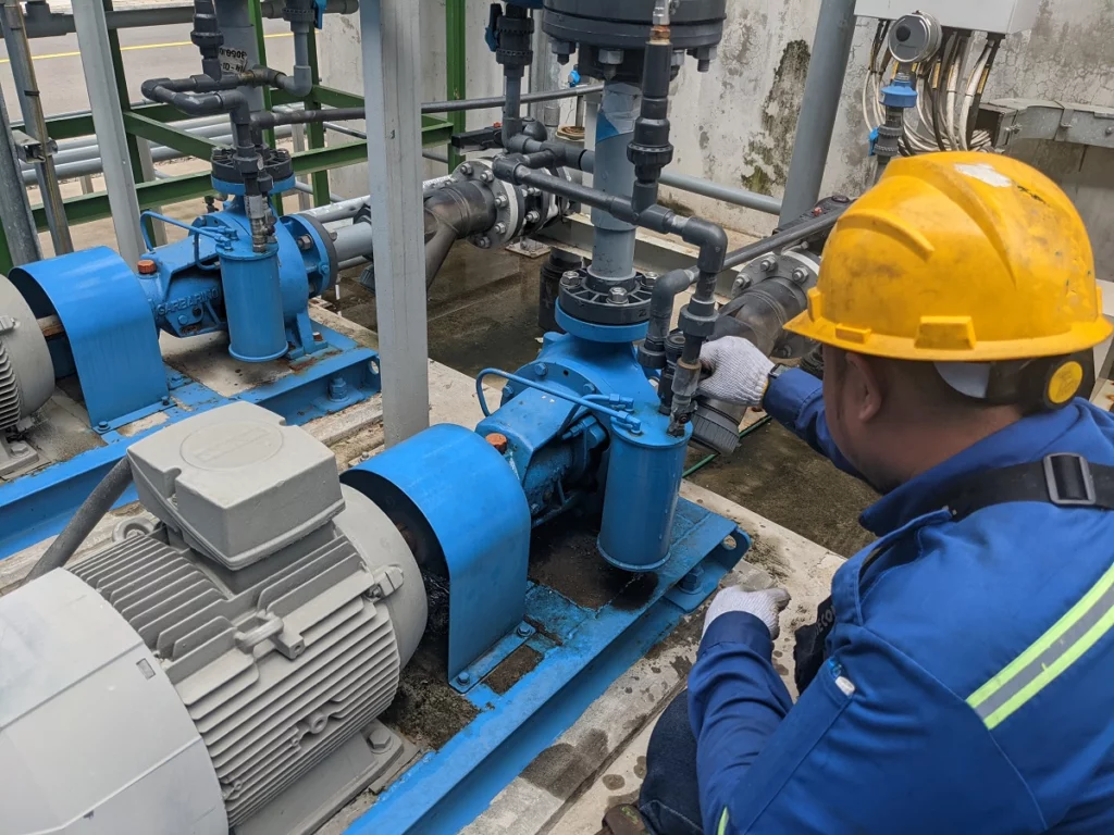 Industrial maintenance technician servicing centrifugal pump connections and fittings to ensure proper function